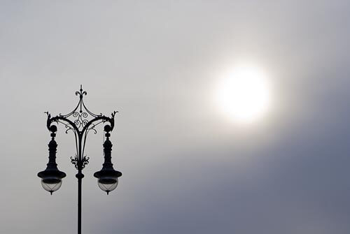 Graphic shot of an ornate lamp post against a cloudy sky in Berlin.