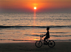 A boy on a bicycle at sunset